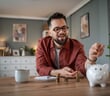 Young,Man,Smiling,As,He,Drops,Coins,Into,A,White