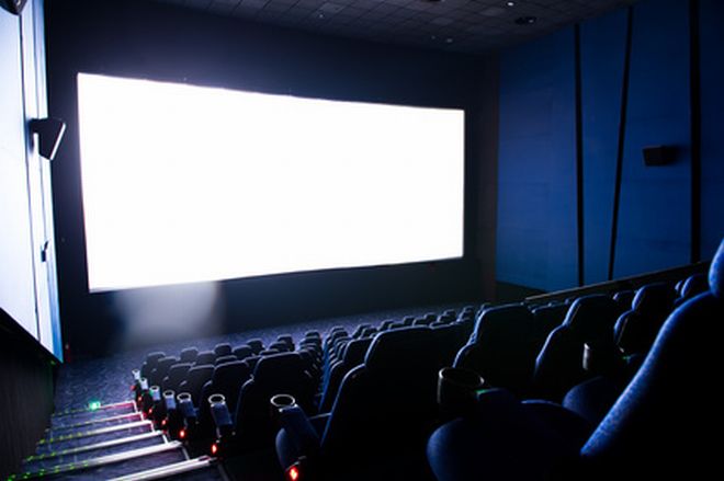 Dark movie theatre interior. screen and chairs.