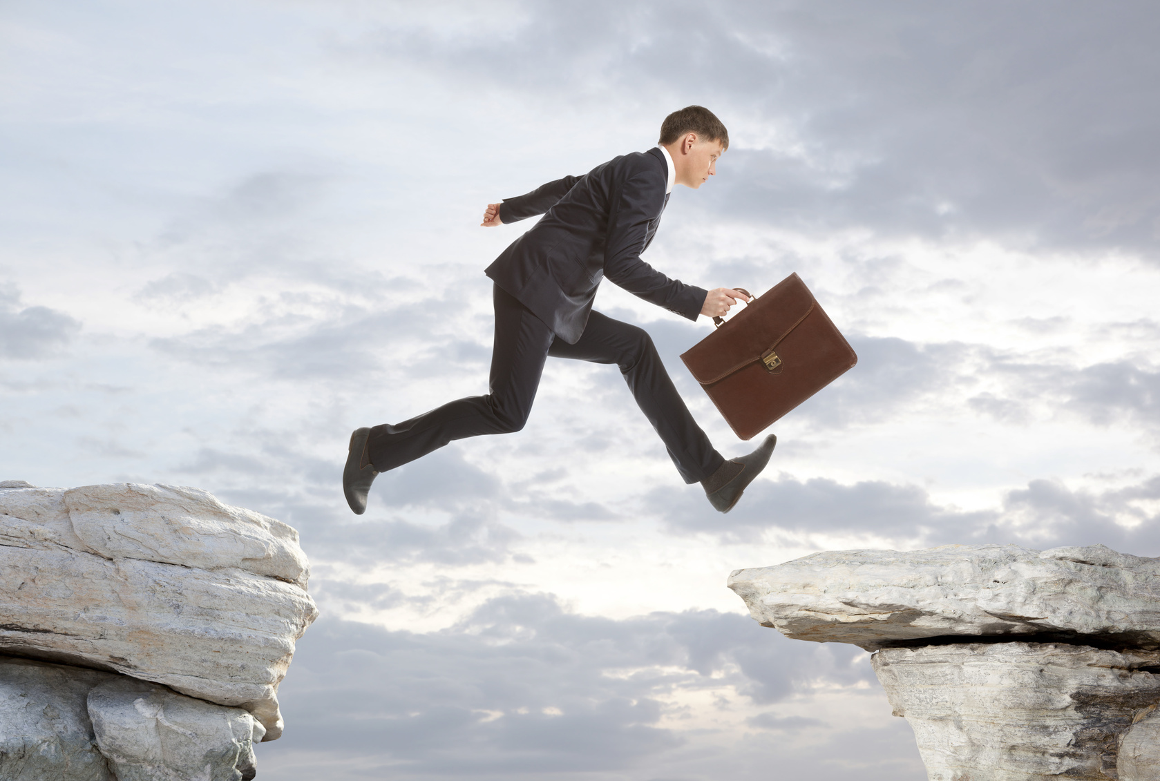 Businessman jumping over rocks