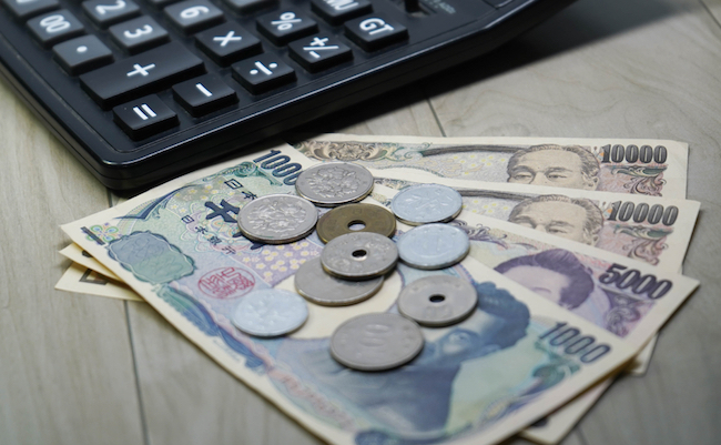 Japanese yen money banknotes and coins with calculator on the table, selective focus