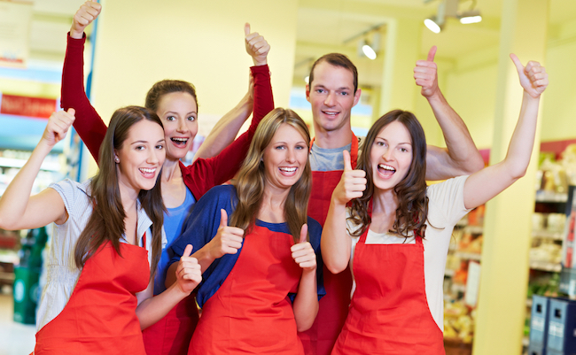 The winning team in the supermarket holds out the thumbs up, laughing