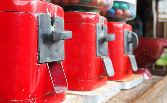 Line,Of,Vintage,Gumball,Machine,On,Wooden,Table