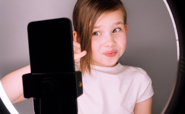 Small,Girl,Using,Camera,Of,Smartphone,In,Front,Of,Ring