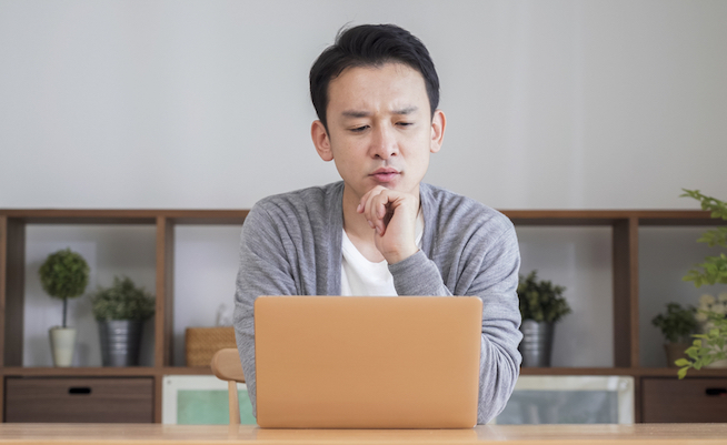 Asian,Man,Using,A,Computer,In,The,Living,Room