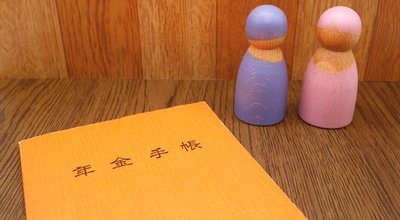 Japan's,Orange,Pension,Book,And,Two,Dolls,Resembling,An,Elderly