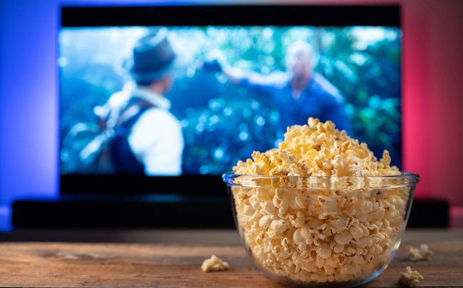 A,Glass,Bowl,Of,Popcorn,And,Remote,Control,In,The