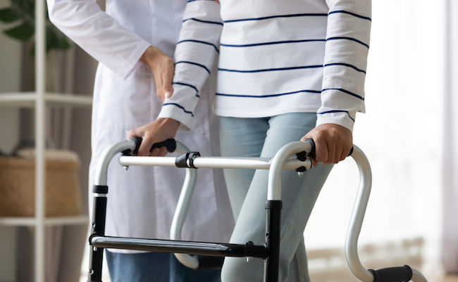 Cropped,Image,Caregiver,Helping,To,Disabled,Patient,Walking,With,Rollator