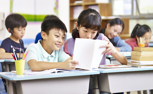 Asian,Elementary,Schoolgirl,And,Schoolboy,Sharing,A,Book,In,Classroom.