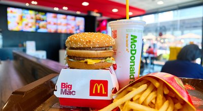 BANGKOK, THAILAND- JULY 26, 2020 : Tasty Big Mac hamburger, french fries, and cup of drink served in retail background of McDonald's restaurant. A popular American fast food chain. Selective focus.