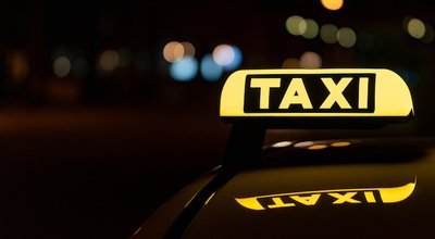 A close-up shot of a taxi sign in the night with bokeh lights in the background