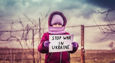 Little refugee girl with a sad look and a poster that says stop war in Ukraine. Social problem of refugees and internally displaced persons. Russia's war against the Ukrainian people.