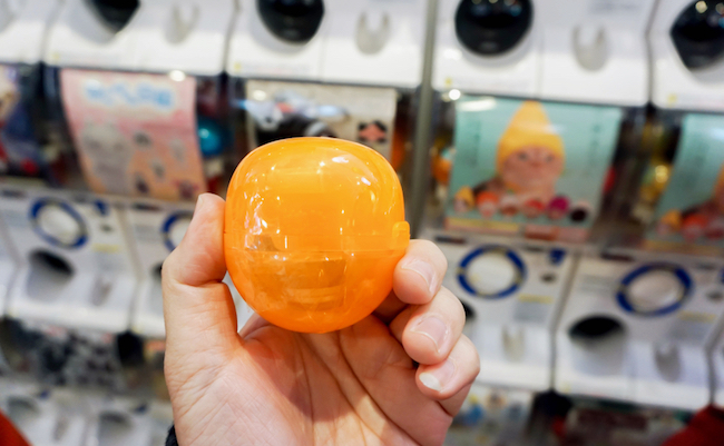 Osaka, Japan, May 19, 2018 : Closeup hand holding and show capsule toy (Gashapong) on blurry gashapong vending machine. Gashapong is one of vending machine dispensed capsule toys popular in Japan.