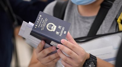 Airport Departures Terminal, HongKong-18July2021: Man hold a blue passport with the reflective golden name Hong Kong Special Administrative Region of the People's Republic of China on the book cover