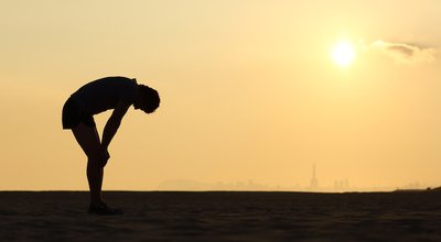 Silhouette of an exhausted sportsman at sunset with the horizon in the background
