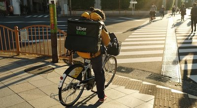 Tokyo, Japan - December 20 2021: An Uber Eats delivery person on a bicycle in Tokyo.