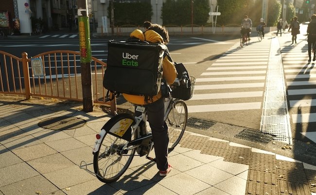 Tokyo, Japan - December 20 2021: An Uber Eats delivery person on a bicycle in Tokyo.