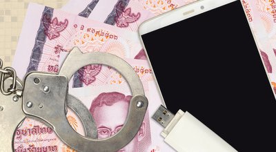 100 Thai Baht bills and smartphone with police handcuffs. Concept of hackers phishing attacks, illegal scam or malware soft distribution