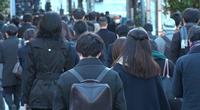 Back shot of unidentified crowd of people walking down the street in busy rush hour. Many commuters going to work. Japanese business man and woman, job and lifestyle concept.