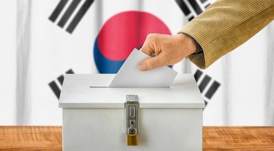 Man putting a ballot into a voting box - South Korea