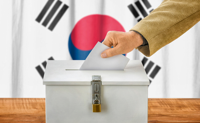 Man putting a ballot into a voting box - South Korea