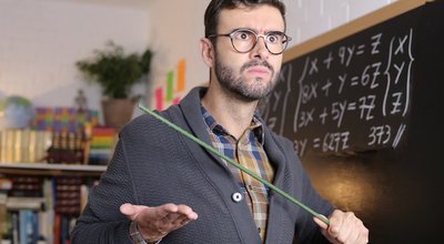 Old fashioned angry teacher holding stick in classroom