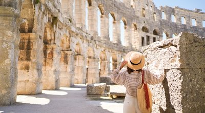 woman in hat stands and looking on Coliseum in Pula Croatia. travel concept.Young woman enjoy summer Italian vacation in Europe.
