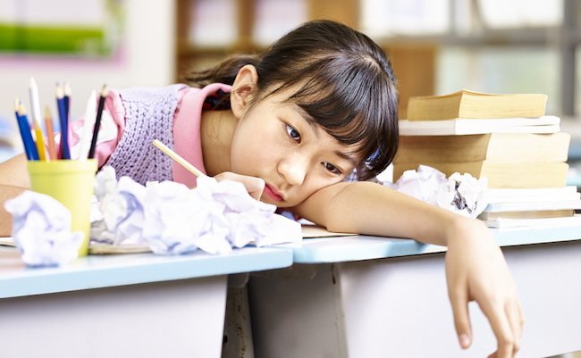 asian elementary school girl frustrated after several failed attempts while writing an essay.