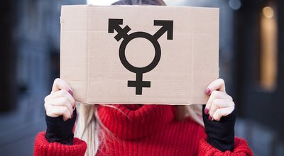 The symbol of the transgender in hands on a cardboard plate, covering (hiding) the face.