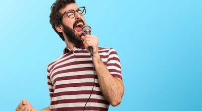 Man with glasses singing with microphone on colorful background
