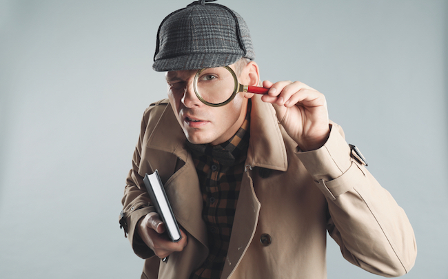 Male,Detective,Looking,Through,Magnifying,Glass,On,Grey,Background