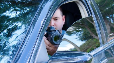 Private investigator on a stakeout is photographing the situation to document the events.