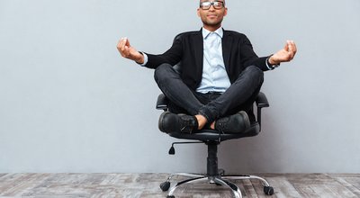 Relaxed handsome african young man sitting and meditating on office chair