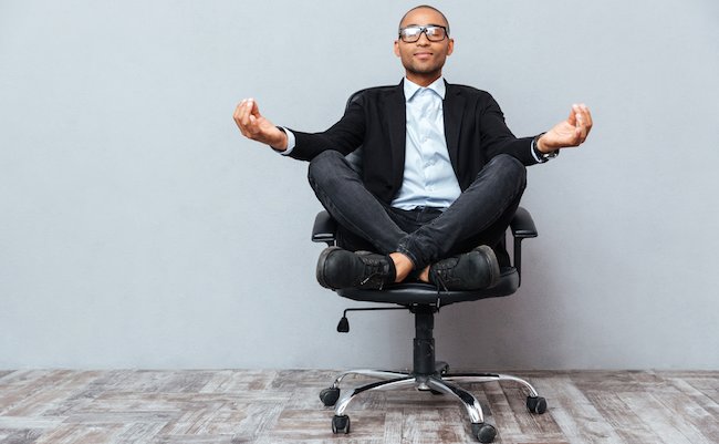 Relaxed handsome african young man sitting and meditating on office chair