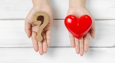 Woman Hands Hold Question Mark and Red Heart on white wood background. Solving Problem of Love Concept.
