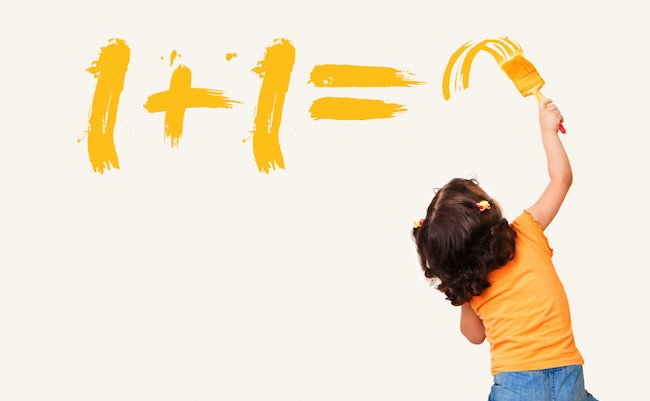 Smart little girl writing the right answer for math equation with painting brush on wall background
