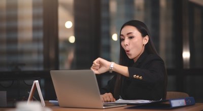 Young adult smart asian business woman in black casual suit using laptop working overtime in urban office.