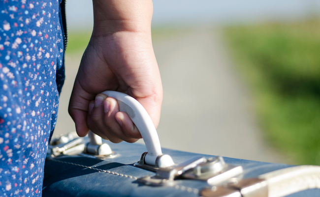 Young,Refugee,Girl,Carrying,Her,Old,Suitcase,While,Walking,On