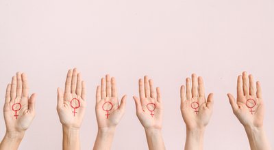 Women with drawn symbols of woman on their palms against color background. Concept of feminism