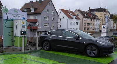 Heilbronn, Germany - November 4, 2021: A Tesla Model 3 charging at the LIDL supermarket DC charging station. Sensor parking for maximum one hour. Rainy autumn day. Selective focus.