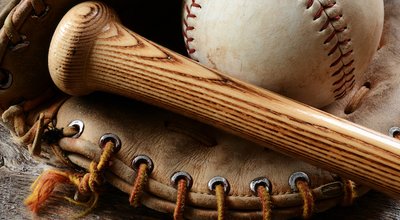 A close up image of an old used baseball, baseball bat, and baseball glove.