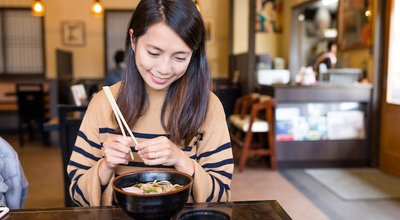 Woman enjoy japanese ramen in restaurant