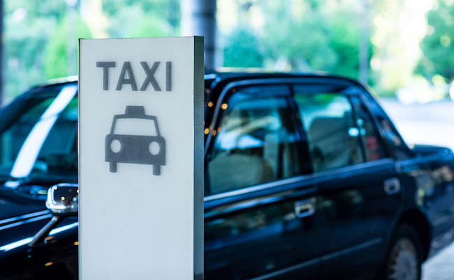 Taxi is waiting for customer behind a taxi stand sign in the front of a hotel, Tokyo, Japan