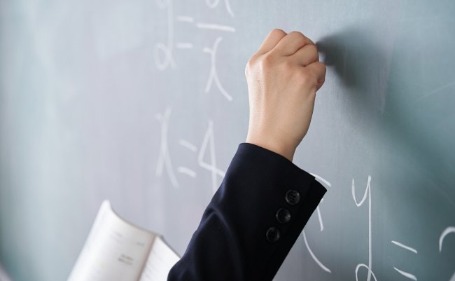A,Japanese,Woman,Teacher,Writes,On,The,Blackboard,In,Her