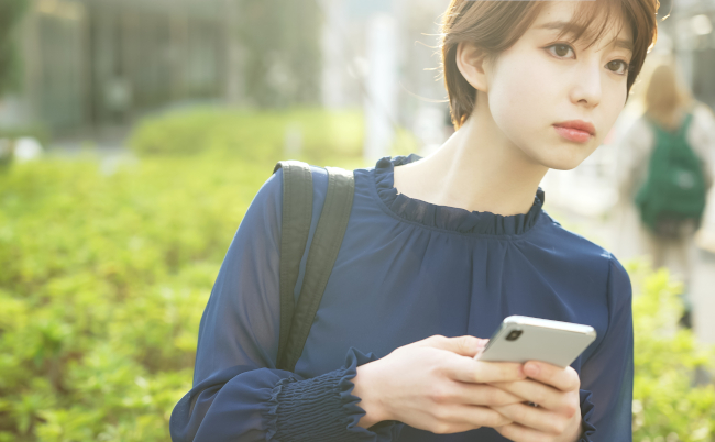 Young,Asian,Woman,Using,A,Smart,Phone,On,The,Street.