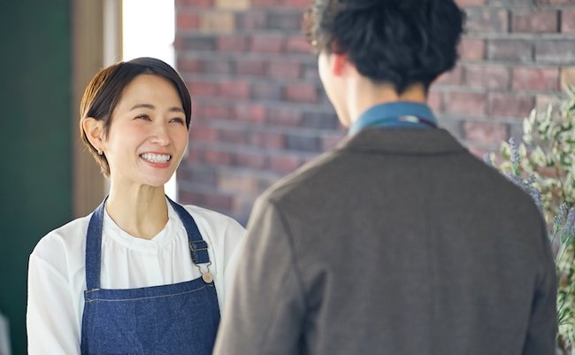 Asian shop clerk and man talking in flower shop.