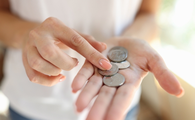Woman counting small coins in her hands close-up. Cheap price, saving money and poverty concept.