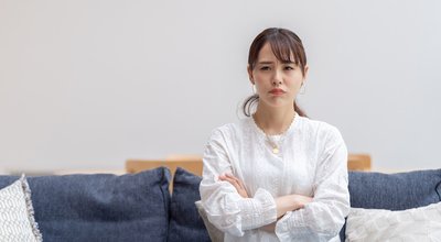 grumpy young asian woman sitting sofa