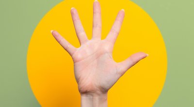 A woman's hand with outstretched fingers. Green background with a yellow circle. Close up. The concept of hypnosis, influence, and psychology