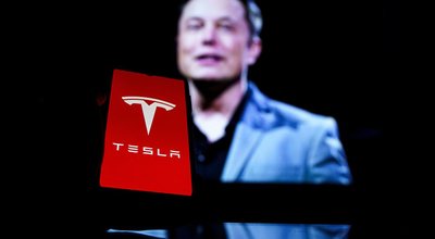 Kaunas, Lithuania 2022 - April 14: Tesla logo on screen and Elon Musk in a background. He is a CEO of Tesla Motors