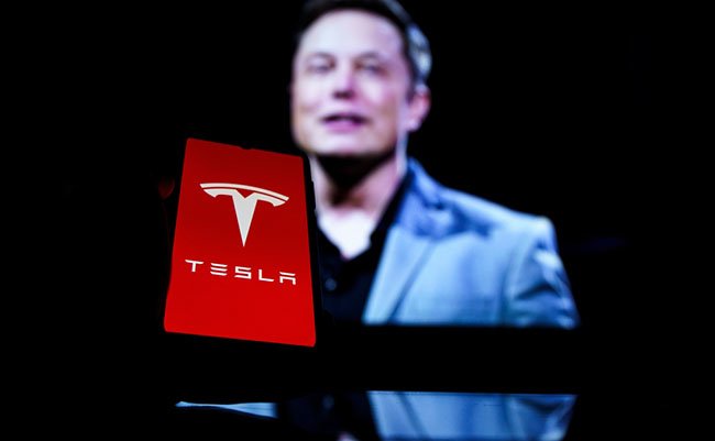 Kaunas, Lithuania 2022 - April 14: Tesla logo on screen and Elon Musk in a background. He is a CEO of Tesla Motors
